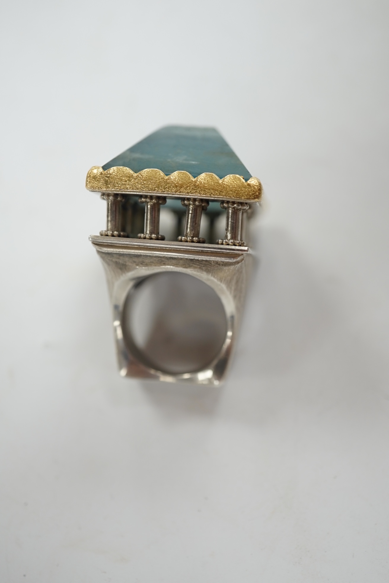 An unusual recent German 925, yellow metal and shaped cut aquamarine set architectural dress ring, the stone weighing approximately 79.00ct, size O/P, gross weight 67 grams. Condition - fair to good